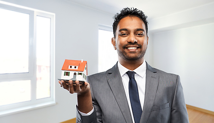 Image showing indian man realtor with house model at new home