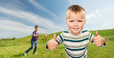 Image showing smiling boy showing thumbs up outdoors