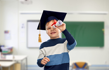 Image showing little boy in mortarboard looking through diploma