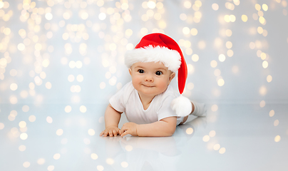 Image showing little baby in santa helper hat lying on floor