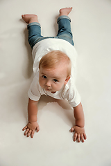 Image showing Little boy lying down on floor and looking up to the side