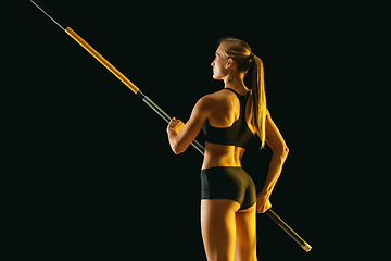 Image showing Female pole vaulter training on black studio background in neon light