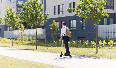 Image showing businessman with backpack riding electric scooter