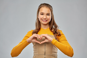 Image showing smiling teenage girl making hand heart