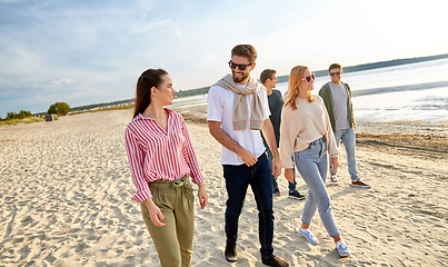 Image showing happy friends walking along summer beach