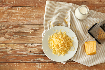 Image showing close up of grated cheese and jug of milk on table