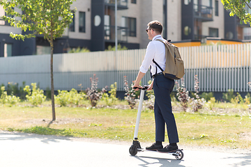 Image showing businessman with backpack riding electric scooter