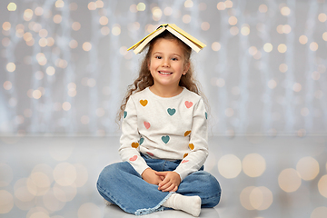 Image showing portrait of smiling girl with book on head