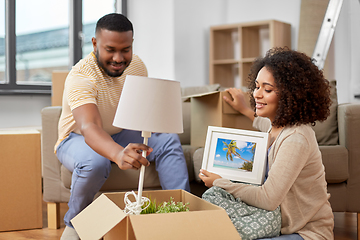 Image showing happy couple packing boxes and moving to new home