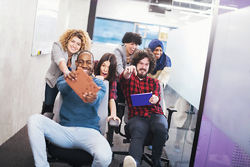 Image showing multiethnics business team racing on office chairs