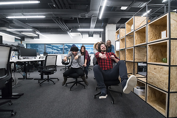 Image showing multiethnics business team racing on office chairs