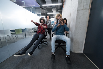 Image showing multiethnics business team racing on office chairs