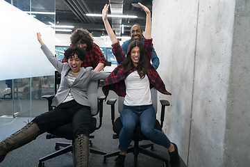 Image showing multiethnics business team racing on office chairs