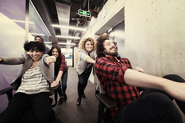 Image showing multiethnics business team racing on office chairs