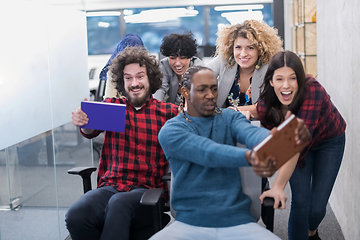 Image showing multiethnics business team racing on office chairs