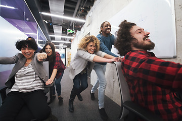 Image showing multiethnics business team racing on office chairs