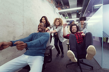 Image showing multiethnics business team racing on office chairs