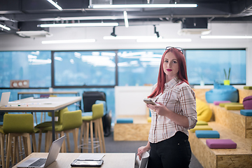 Image showing redhead businesswoman using mobile phone at office