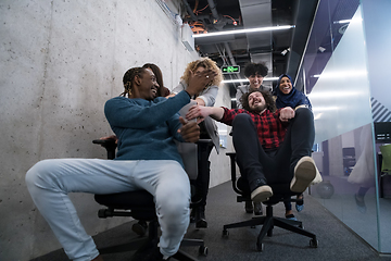 Image showing multiethnics business team racing on office chairs