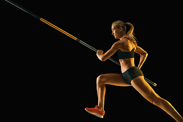 Image showing Female pole vaulter training on black studio background in neon light