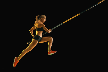 Image showing Female pole vaulter training on black studio background in neon light