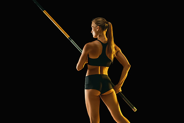 Image showing Female pole vaulter training on black studio background in neon light