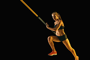 Image showing Female pole vaulter training on black studio background in neon light