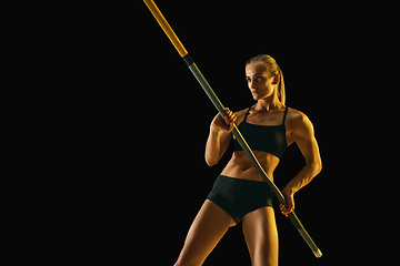 Image showing Female pole vaulter training on black studio background in neon light