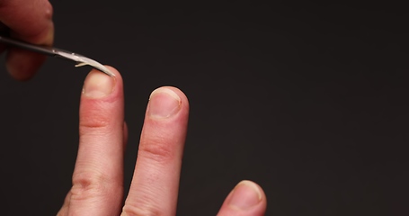 Image showing Man cuts fingernail for himself