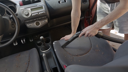 Image showing Man cleaning dirty car interior with vacuum cleaner