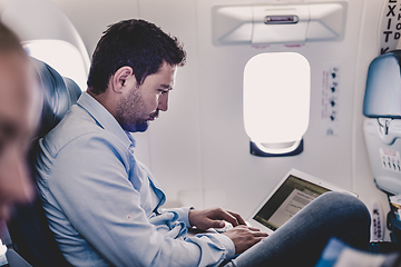 Image showing Businessman working with laptop on airplane.