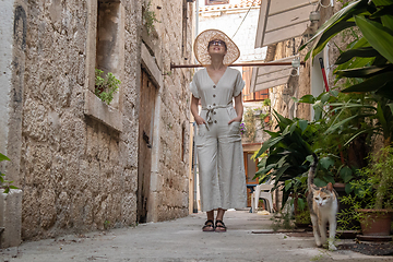 Image showing Beautiful blonde young female traveler wearing straw sun hat sightseeing and enjoying summer vacation in an old traditional costal town at Adriatic cost, Croatia.