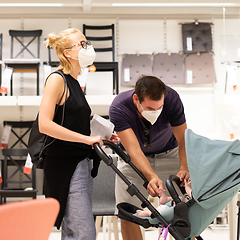 Image showing Young couple with newborn in stroller shopping at retail furniture and home accessories store wearing protective medical face mask to prevent spreading of corona virus when shops reopen.