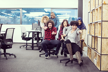 Image showing multiethnics business team racing on office chairs