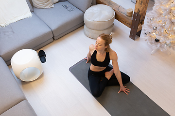 Image showing Beautiful blonde woman doing home workout indoors. Woman practice yoga at home. Fit girl using workout tutorials for healthy active lifestyle. Woman using quarantine for home workouts.