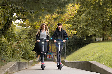 Image showing Trendy fashinable teenagers riding public rental electric scooters in urban city park. New eco-friendly modern public city transport in Ljubljana, Slovenia