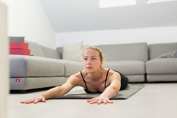 Image showing Beautiful blonde woman doing home workout indoors. Woman practice yoga at home. Fit girl using workout tutorials for healthy active lifestyle. Woman using quarantine for home workouts.