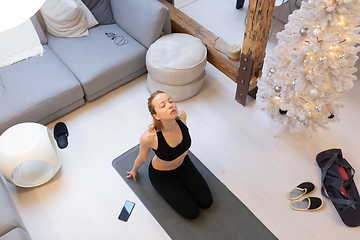 Image showing Beautiful blonde woman doing home workout indoors. Woman practice yoga at home. Fit girl using workout tutorials for healthy active lifestyle. Woman using quarantine for home workouts.