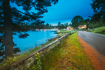 Image showing Sweden. Road To Beautiful Swedish Village near Lake. Wooden Log Cabin Houses In Summer Evening Night. Lake Or River Landscape