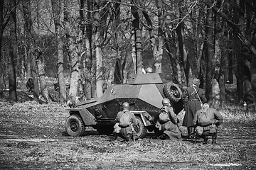Image showing Group Of Reenactors Dressed As Russian Soviet Red Army Soldiers Of World War II Go On Offensive Under Cover Of Armored Soviet Scout Car. Historical Reenactment In Forest