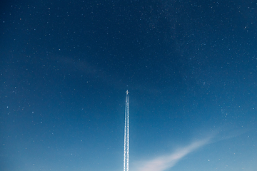 Image showing Contrail In Blue Sky. Aircraft Plane In Starry Night Sky Background. Plane Flying Up To Space With Stars On Backdrop. Travel Trip Concept. Copy Space