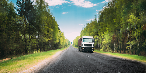 Image showing Truck, Tractor Unit, Prime Mover, Traction Unit In Motion On Country Road Through Forest, Freeway. Cloudy Sky Above Asphalt Motorway, Highway. Business Transportation