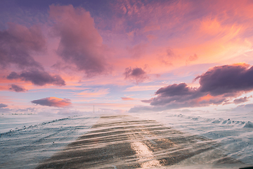 Image showing Snow-covered Open Slippy Road During A Snowstorm Blizzard In Winter. Altered Colorful Sunset Sunrise Sky. Dangerous Motion