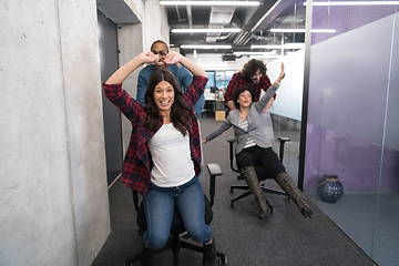 Image showing multiethnics business team racing on office chairs