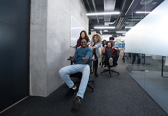 Image showing multiethnics business team racing on office chairs