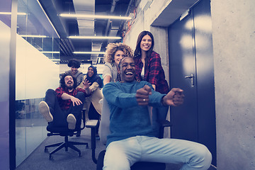 Image showing multiethnics business team racing on office chairs