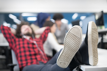 Image showing software developer resting with legs on desk