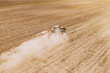 Image showing Aerial View. Tractor With Seed Drill Machine Sowing The Seeds For Crops In Spring Season. Beginning Of Agricultural Spring Season. Countryside Rural Field Landscape