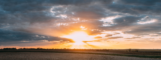 Image showing Sun Shine During Sunset Above Empty Spring Countryside Rural Soil Landscape. Field Under Sunny Spring Sky. Agricultural Landscape With Copy Space. Panorama