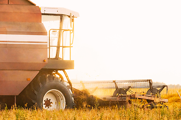 Image showing Combine Harvester Working In Field. Harvesting Of Wheat In Summer Season. Agricultural Machines Collecting Wheat Seeds